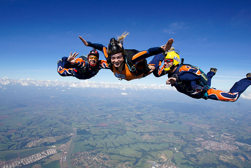 Aluna com dois instrutores em queda livre durante curso AFF