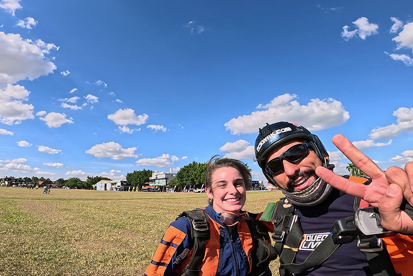 aluna e instrutor após salto de paraquedas